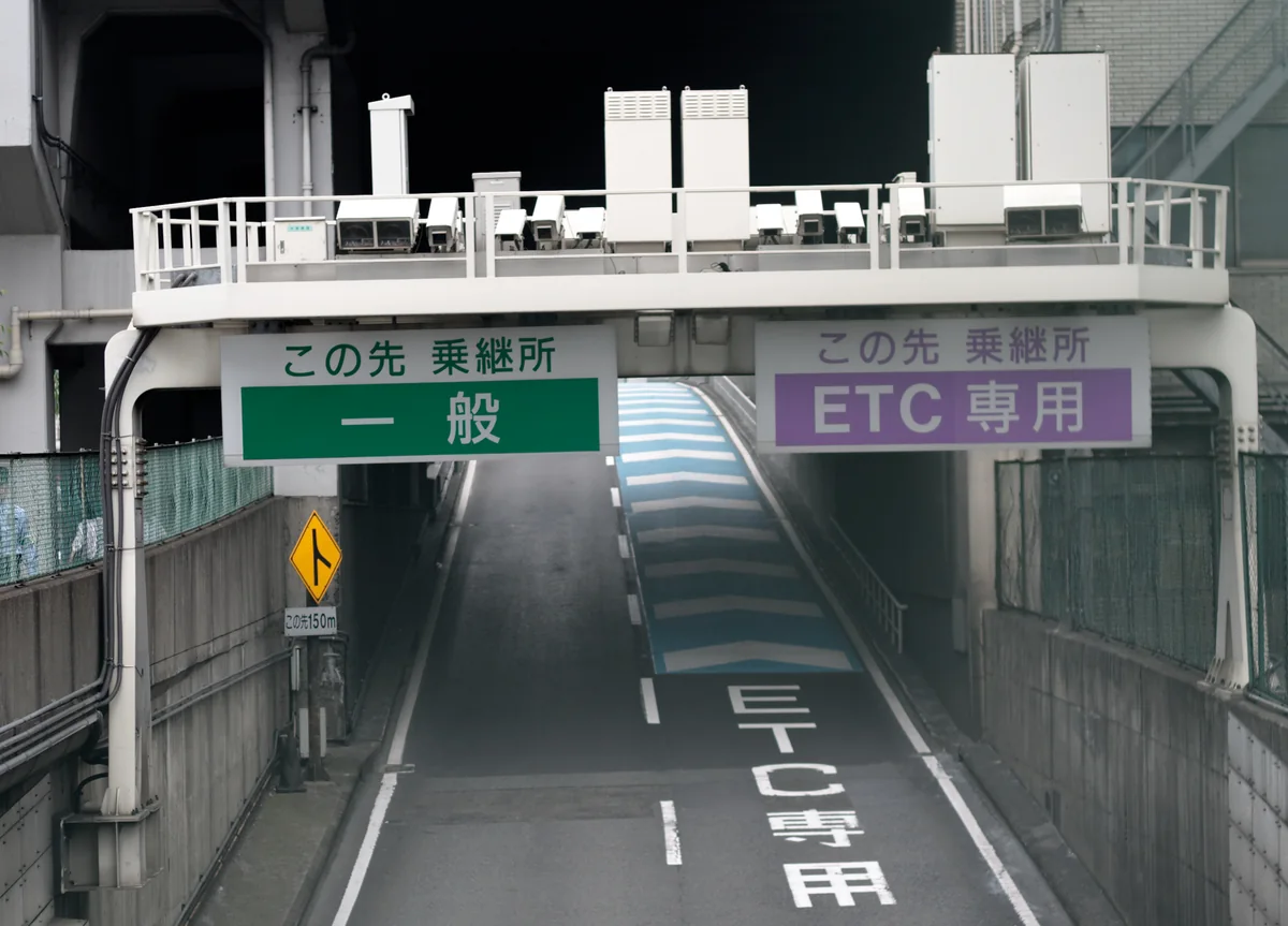 Overhead lane signs at a toll gate: a green sign reading 一般 on the left and a purple sign reading ETC専用 on the right